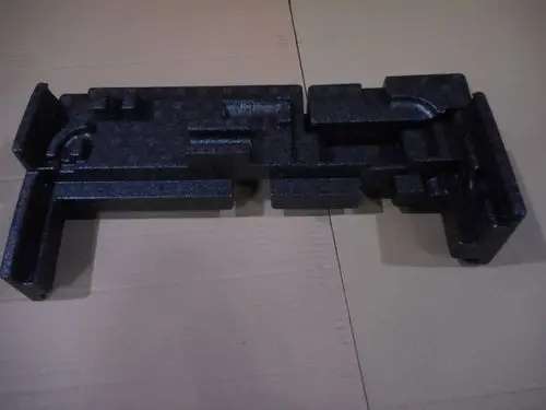 Schwarzer Kunststoffblock mit spezifischen Aussparungen, vermutlich für einen hydraulischen Deckel. Produkt von Remeha, auf einer braunen Pappe liegend.